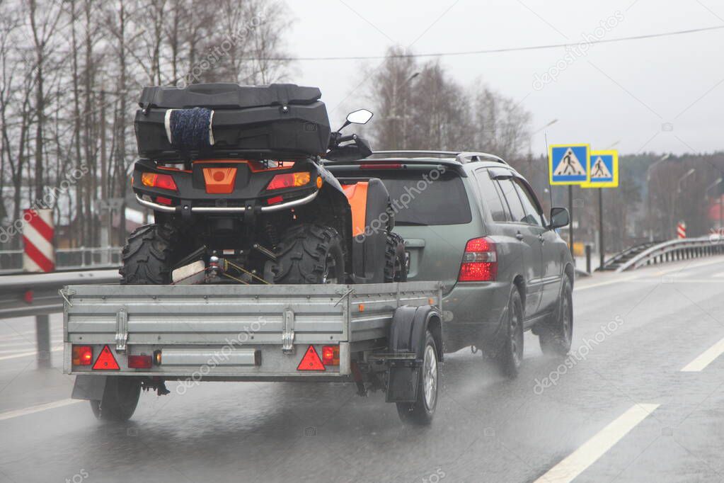 Transportation of technical equipment for extreme active sports, AWD car with a single-axle trailer on the asphalt highway road