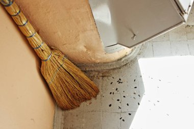 Kirli zemini olan bir çöp kanalının yanındaki süpürge, bir apartmanın merdiven boşluğunu süpürüyor.