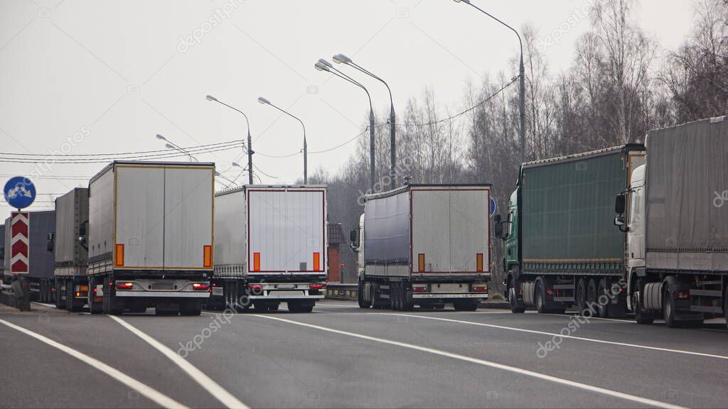 Closed border, semi trucks queue on anti viral quarantine control point at spring day, internation logistics trouble illustration concept