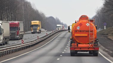 Rus yazıtlı yeni turuncu varili olan yakıt kamyonu. INFLAMMMable ve devam eden kamyonlar bahar günü banliyö otobanında yol alıyorlar. Rusya 'da dağıtım trafiği, ADR ulaşım lojistiği.