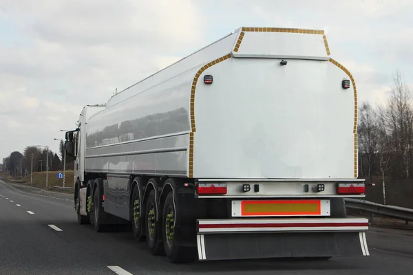 春の日にアスファルト高速道路上を移動する現代の白い燃料トラックのガソリンタンカー リア側のビュー Adr危険な貨物 バレル外部表面上のテキストのためのコピースペース — ストック写真