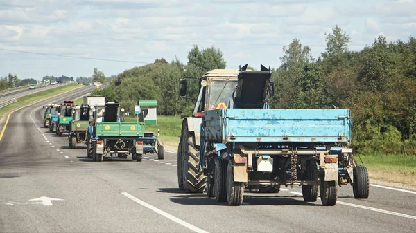 晴れた夏の日にアスファルト郊外の高速道路にフラットベッドトレーラーを持つ多くのトラクター 農業機械化 視点でリアサイドビュー — ストック写真