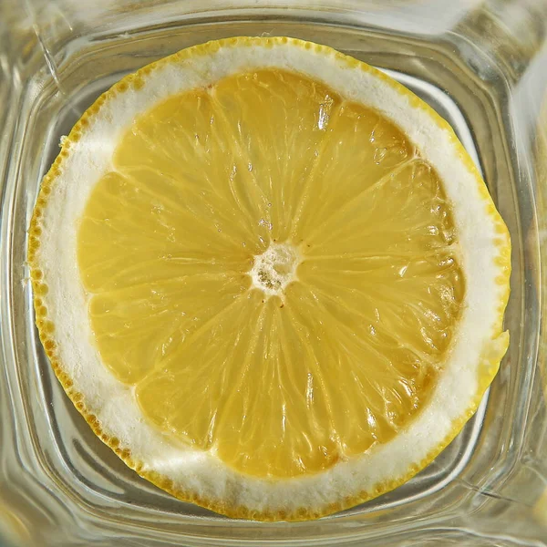 Round juicy lemon in a square glass close up