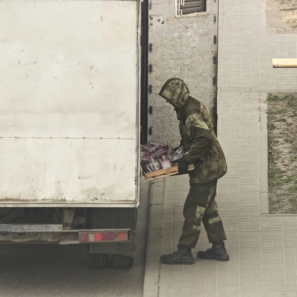 フード付きの迷彩服を着た男がトラックからパンをアンロードします — ストック写真