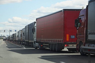 Drivers strike, big queue of trucks with semi-trailers to the sanitary and weight control point in Sunny summer day, rear side view in perspective clipart