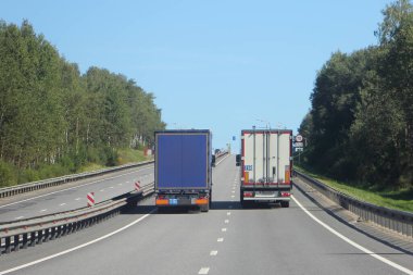 Mavi ve beyaz iki kamyonet Sunny yaz banliyö otoyolunda dikiz aynasından Avrupa 'da karayolu kargo taşımacılığı lojistiği ile sevkiyat