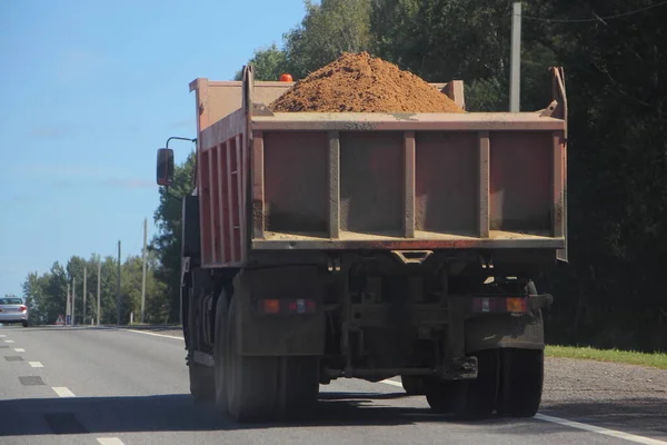 晴れた夏の日に郊外の高速道路で砂を積んだダンプトラック 建設資材の道路輸送 — ストック写真