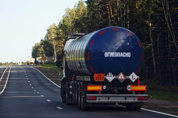 深蓝色半卡车沥青油罐车 带有99 3575级危险标志 夏天在柏油公路上的桶道上有俄罗斯字样Flammable 森林背景 Adr危险货物 — 图库照片