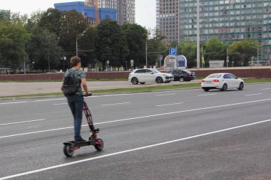 Elektrikli scooterlı bir adam şehirde bir otoyolda hızlı gidiyor, şehir yol güvenliği çocukları...