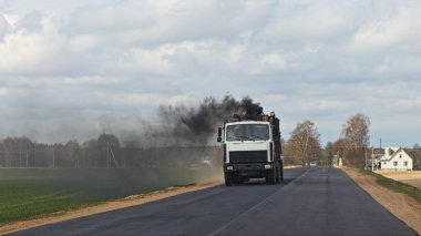 Kırsal kesimin arka planında dizel bir kamyon tüttürmek, araçlardan kaynaklanan zararlı emisyonlar, çevre kirliliği