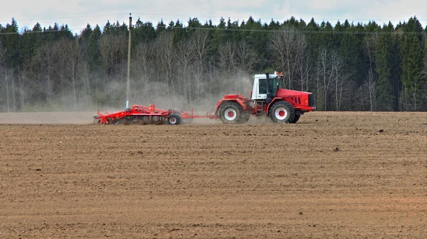 Een Uitgestrekt Bruin Geploegd Beteeld Veld Met Grote Rode Trekker — Stockfoto