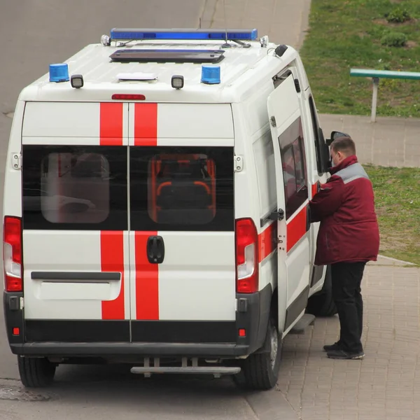 Врач Красной Одежде Садится Красно Белую Машину Скорой Помощи Синими — стоковое фото