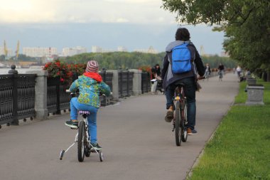 Bir çocuk ve baba bisikletleri bir yaz günü Park 'taki toprak setinde bisiklet sürerler, sokak yolundaki arka manzara, açık hava sporları aile eğlencesi