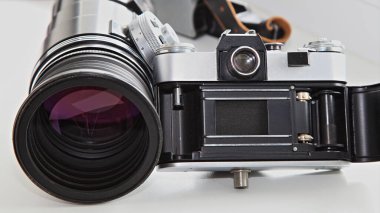Eski bir SLR kameranın arka tarafında film sürücüsü mekanizması ve 300 mm yakınlaştırma lensinin yanında bir deklanşör var.