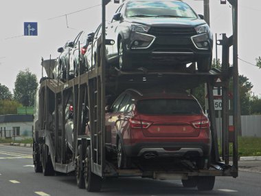 İki katlı, iki eksenli araba taşıyıcı kamyonu varoş otobanında yarı karavan sürücüsü, dikiz görüşü yakın, yeni Rus arabaları lojistik dağıtımı