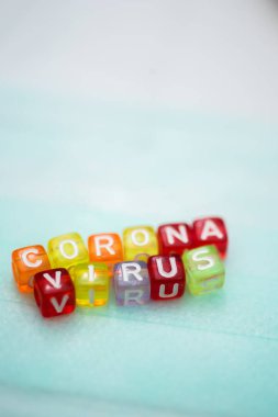 Yüz maskesi üzerine renkli kelime CORONA VIRUS İngiliz alfabe küpü, seçici odaklanma