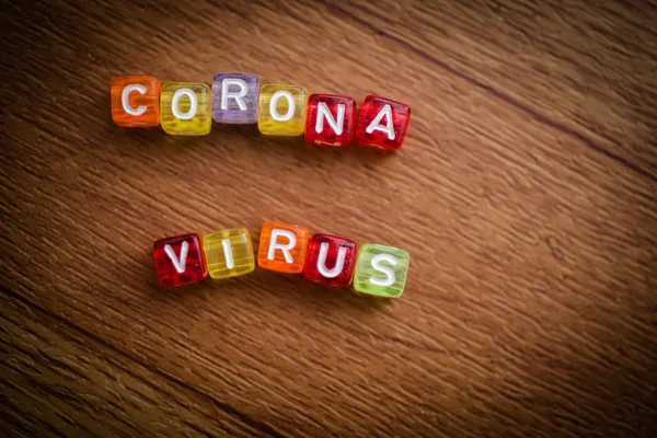 Kahverengi arkaplan üzerine renkli kelime CORONA VIRUS İngiliz alfabe küpü, seçici odak