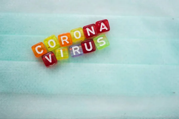 Yüz maskesi üzerine renkli kelime CORONA VIRUS İngiliz alfabe küpü, seçici odaklanma
