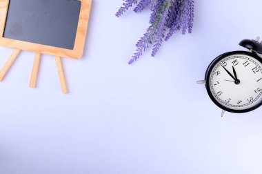 Kavramsal, siyah tahta beyaz bir masada. Çiçek ve saat, kopyalama alanı yazma işlemine hazır