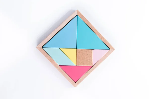 Tahta yapboz elemanı. El bulmacanın son elementini belirler. Mantıklı düşünme kavramı. Ahşap arka planda geometrik şekiller. Tetris oyuncak tahta bloklar.