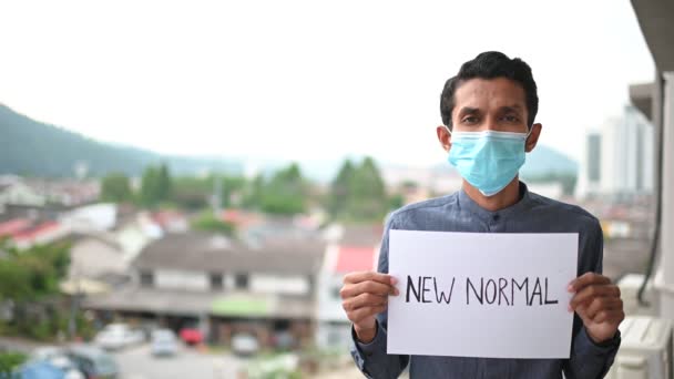 医療用マスクの若いアジア人男性は カメラを見て 病気やほこりを防ぐために New Normal を描き 午後5時 コロナウイルスのパンデミック予防を示しています スペースのコピー — ストック動画
