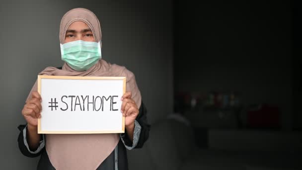 Молодая Красивая Мусульманка Медицинской Маске Глядя Камеру Показывая Рисунок Stayhome — стоковое видео