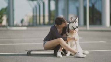 Sokakta köpeğine sarılan genç bir kadın.
