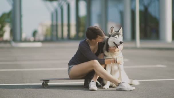 Ung kvinna på gatan kramar sin husky hund — Stockvideo