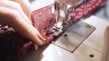 Dikiş makinesinde çalışan kadınların yakın çekim görüntüleri.