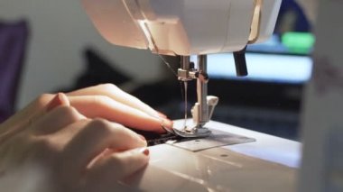 Dikiş makinesinde çalışan kadınların yakın çekim görüntüleri.