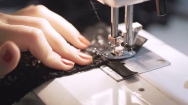 Dikiş makinesinde çalışan kadınların yakın çekim görüntüleri.
