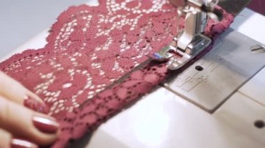 Dikiş makinesinde çalışan kadınların yakın çekim görüntüleri.