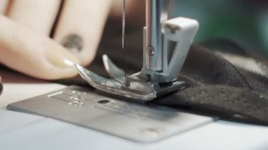 Dikiş makinesinde çalışan kadınların yakın çekim görüntüleri.