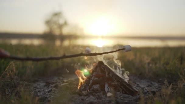 Prażenie marshmallows nad ognisko na plaży o zachodzie słońca — Wideo stockowe