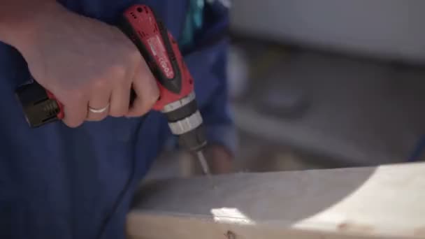 Man met behulp van een stalen boor en de gebruikelijke schroevendraaier op houten plaat — Stockvideo