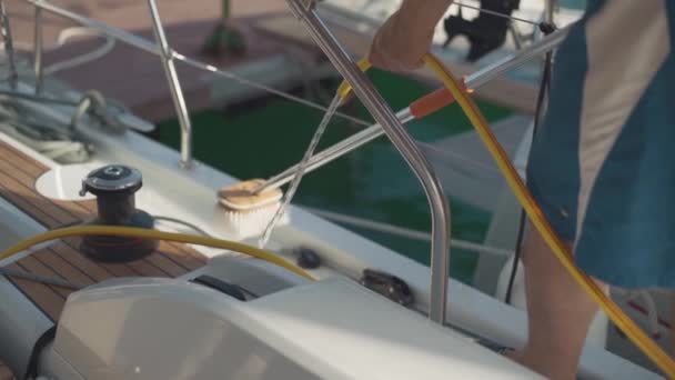 Людина миє яхту шлангом з повільним рухом води — стокове відео