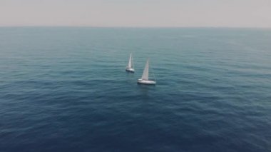 Yüzen insanların okyanus siluetlerindeki iki yatın havadan görünüşü