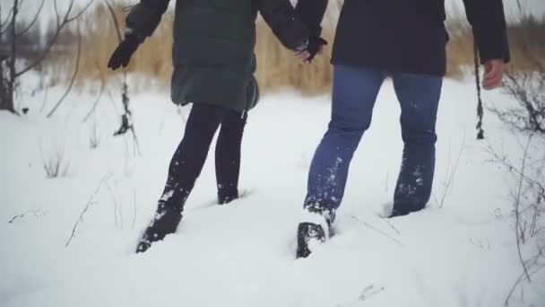 Un homme avec une femme marche à travers la neige profonde — Video