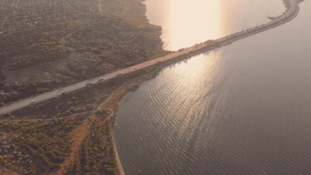 Повітряний вид на дорогу, що проходить по морських автомобілях, проїжджає через міст на заході сонця — стокове відео