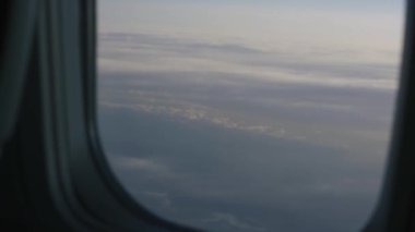 Uçağın penceresinden bulutlar görünüyor.