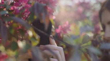 Kızıl saçlı kadın bahar çiçeklerinin fotoğraflarını çekiyor. Sakura çiçeklerinin.