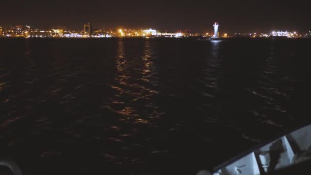 Gemi gece fenerin yanındaki limana gidiyor. — Stok video