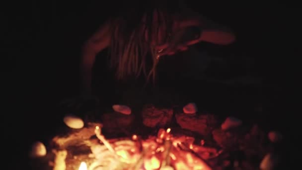 Ведьма совершает ритуал вуду возле костра ночью — стоковое видео