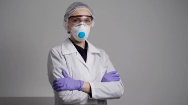Sağlık uzmanı kadın elleri çapraz pozlar veriyor koruyucu başlık, gözlük ve maske takıyor.