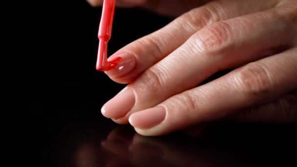 Руки девушки с абманикюром. гель-лак на ногтях. нанесение гель-лак на ногти на черном фоне — стоковое видео