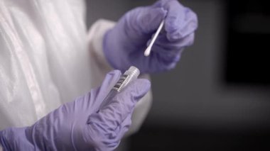 Salgın Covid-19. Laboratuvar teknisyeni içinde virüs örneği olan bir test tüpü tutuyor..