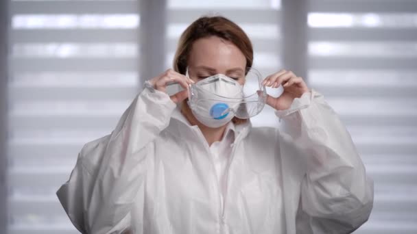 Pandemia Covid-19. Enfermeira após um longo turno, remove seu terno protetor e máscara . — Vídeo de Stock
