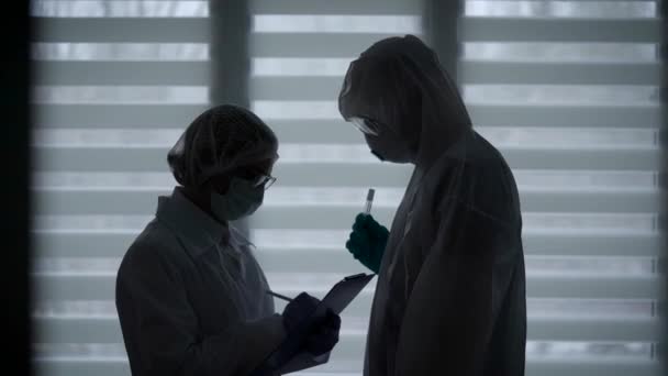 Una escena sombría en una institución médica. El virólogo se reúne con una enfermedad infecciosa para transmitir las pruebas a los pacientes — Vídeo de stock