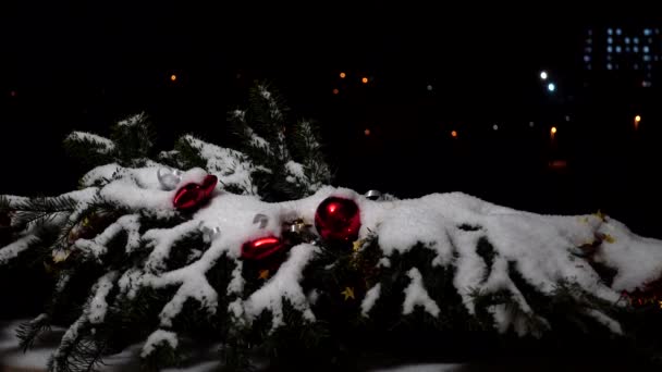 Branches d'arbre de Noël décorées de jouets sous la neige. Tournage nocturne sur fond de ville nocturne .