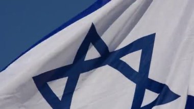 Mavi gökyüzünün arka planına karşı İsrail bayrağı.